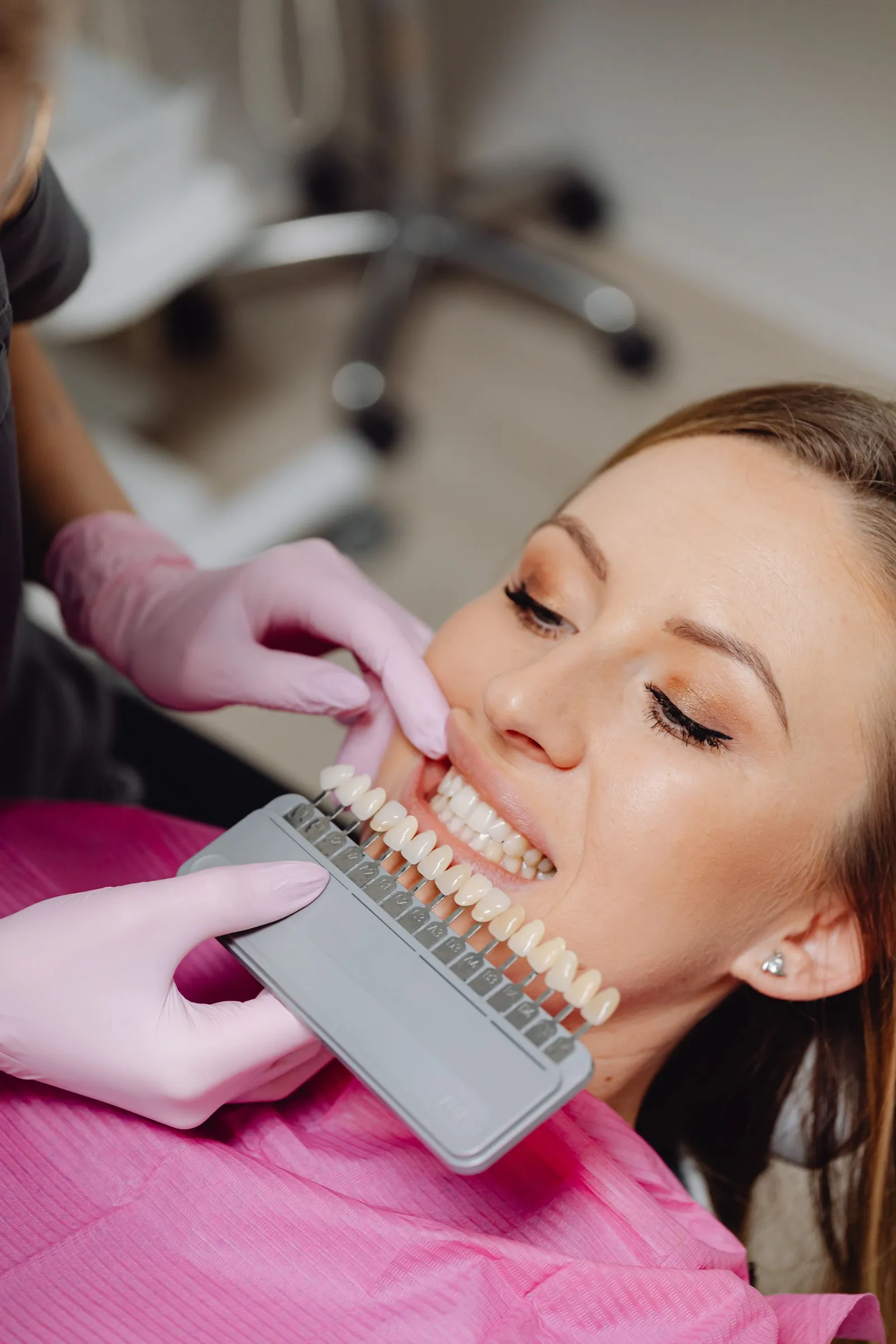 Dentista comparando la guía de color junto a la sonrisa de una paciente