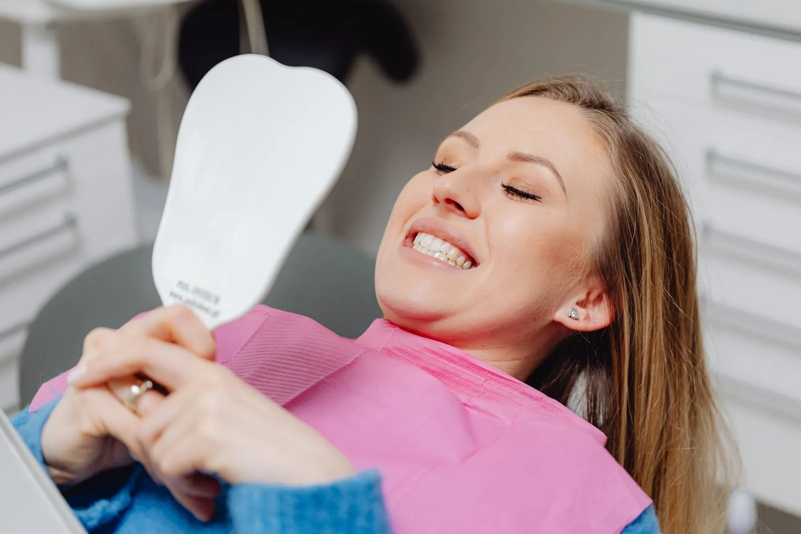 Paciente mirándose la sonrisa en un espejo con forma de diente