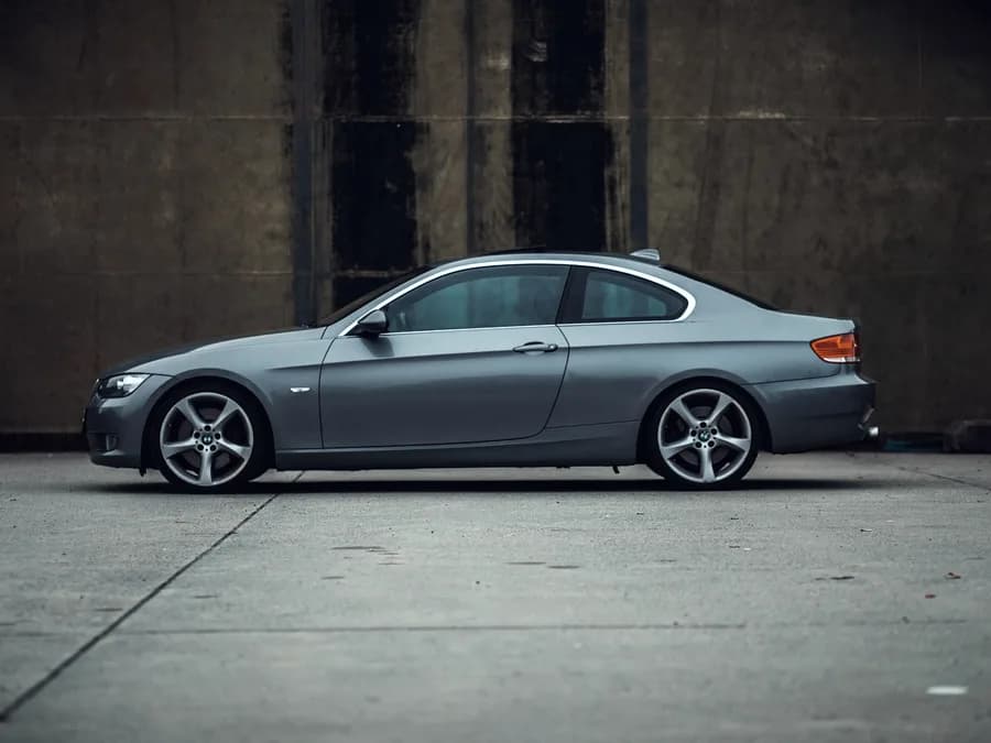 Perfil de un BMW Serie 3 Coupé gris ante un muro de hormigón